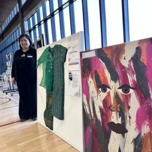 Article writer Giselle General stands by her exhibit booth, two almost life-sized art pieces. Credit: Alberta Chronicle